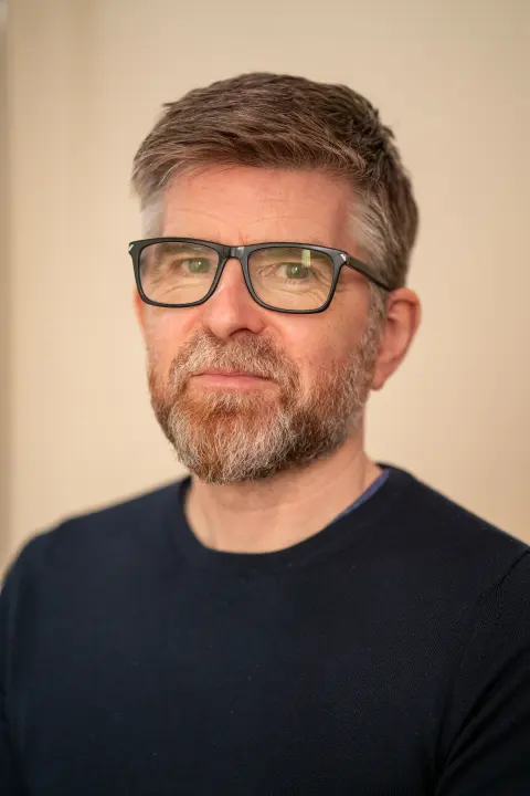 Studio portrait of Phil Alderson wearing glasses